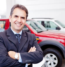 Business man working at a car dealer smiling.jpeg