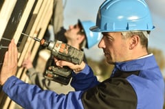 Construction worker using electric drill on building site.jpeg